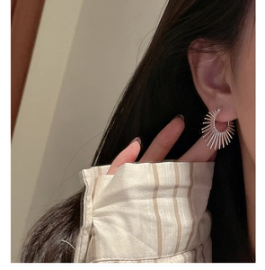 Gros plan de boucles d'oreilles argentées en forme d'éventail portées sur l'oreille