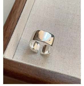 Detailed view of glossy S925 sterling silver wide band open ring on linen tray