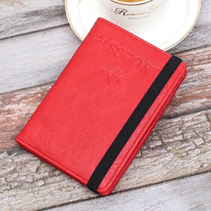 Close-up of red lychee leather passport holder with elastic strap and aircraft embossing