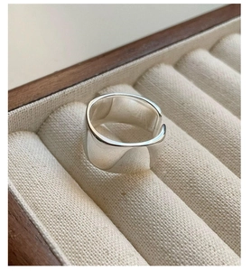 Close-up of a minimalist wide silver ring with polished mirror surface in a wooden box