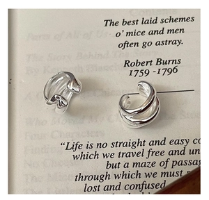 Macro detail of triple-layered sterling silver ear cuffs on a vintage book page
