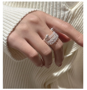 Detail of S925 sterling silver multilayer chain ring worn on finger over knit fabric