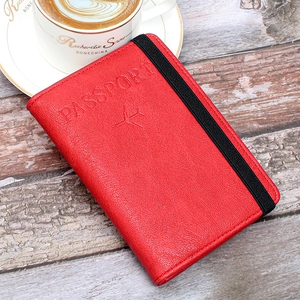 Detail of red leather passport holder with elastic band on a vintage wooden desk