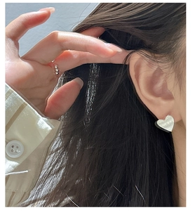 Détail d'une boucle d'oreille cœur brossé et d'une bague ouverte à micro-diamants