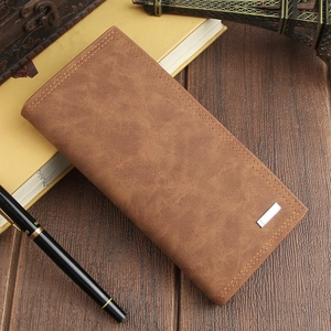 Close-up of a vintage brown leather long wallet on a desk with a metal clasp detail
