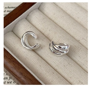 Close-up of triple-layered silver ear cuffs on cream velvet jewelry display box