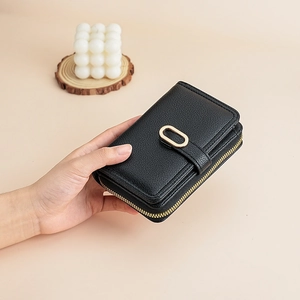 Close-up of black lychee grain leather wallet featuring gold oval buckle and metal zipper