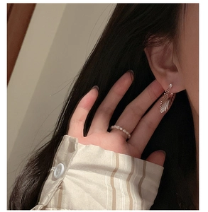 Gros plan d'une boucle d'oreille éventail en argent et d'une bague en perles fines