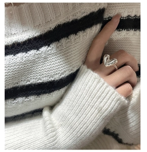 Detail of a polished S925 sterling silver heart ring on a striped fabric background