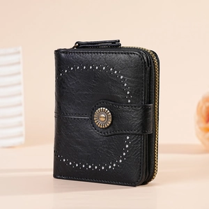 Detail of black faux leather wallet with laser-cut C-pattern and vintage floral metal stud