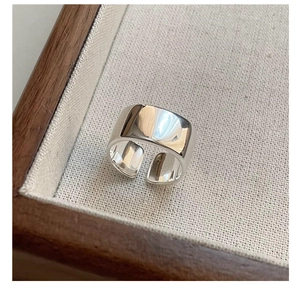 Macro shot of minimalist wide S925 sterling silver open ring on textured linen tray