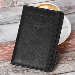 Close-up of black PU leather passport holder with embossed logo on a wooden table