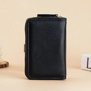 Detail of black lychee grain leather wallet featuring a gold zipper and vertical structure