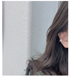 Macro detail of silver layered ear cuff showing polished metallic texture on ear