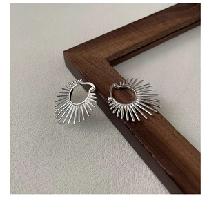Gros plan de boucles d'oreilles géométriques en argent sur fond minimaliste texturé