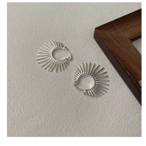 Détail macro de boucles d'oreilles créoles S925 en argent au design soleil géométrique chic