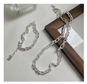 Macro shot of silver paperclip chain necklace and bracelet set with lava texture finish