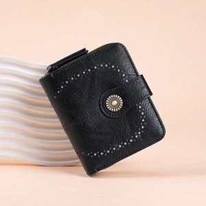 Close-up of black retro wallet with sunflower metal buckle and heart perforated details