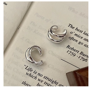 Detail view of triple-layered sterling silver ear cuffs on a vintage book page