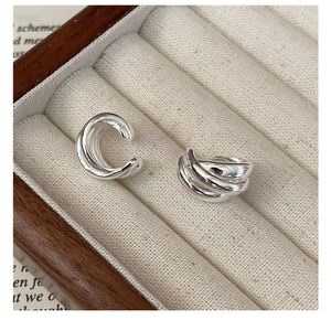 Detail of S925 sterling silver triple-layer ear cuff on a beige jewelry display tray