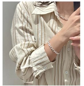 Detail view of S925 sterling silver paperclip chain bracelet on a model's wrist