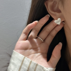Boucles d'oreilles cœur en argent S925 et bague perlée sur mannequin avec texture brossée