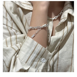 Detailed view of silver paperclip link bracelet and necklace set on shirt cuff