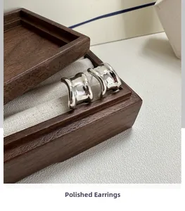 Close-up of chunky polished S925 sterling silver hoop earrings on a display tray