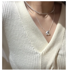Close-up of double-layer S925 sterling silver necklace with unique fluid pendant on knitwear