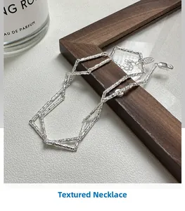 Detail of S925 sterling silver necklace with textured finish on a wooden frame