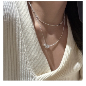 Close-up of layered S925 silver necklaces featuring a minimalist bar and geometric pendant
