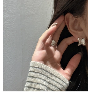 Detail of minimalist S925 silver earring with liquid metal texture and irregular curves