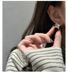 Close-up of a minimalist silver geometric earring and matching ring on model with high polish