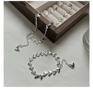 Detailed view of S925 sterling silver heart-shaped necklace and bracelet set on display