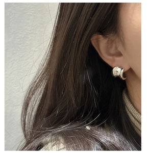 Close-up of polished S925 sterling silver chunky curved earrings on a model ear