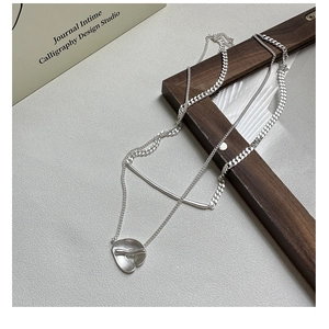 Detail of matte S925 sterling silver layered necklace with OT buckle and metallic charms