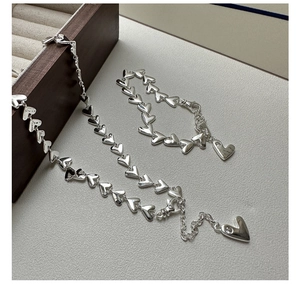 Macro shot of silver heart chain bracelet and necklace set with sparkling pendant