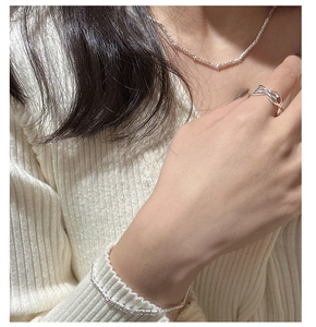 Detail of silver twisted texture necklace and bracelet with bow ring on model