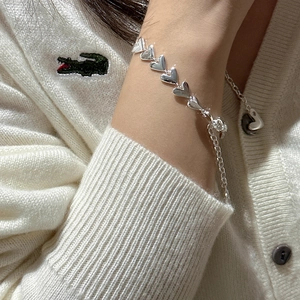 Chunky S925 sterling silver heart bracelet on wrist with a soft knit sweater