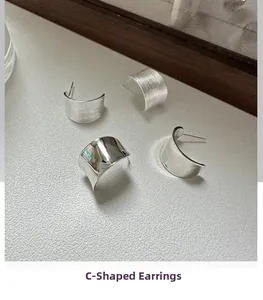 Detailed view of silver C-shaped earrings with matte brushed and polished finishes