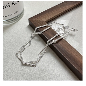 Detailed view of S925 sterling silver textured necklace with clasp on wooden frame