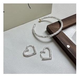 Detail of S925 silver open bangle and heart earrings with vintage floral relief
