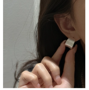 Close-up of minimalist S925 sterling silver wide hoop earring with brushed matte finish texture