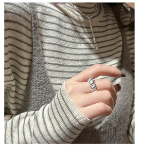 Close-up of S925 sterling silver croissant ring on finger with elegant knitwear