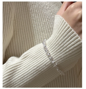 Detail view of S925 sterling silver double-row chain bracelet on a beige knit sleeve