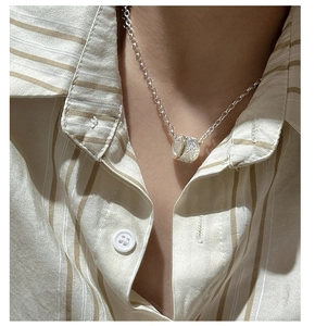Detail of S925 sterling silver cylinder pendant with vine engraving worn on neck