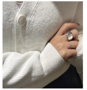 Detail shot of a wide textured S925 silver wave ring and a minimalist round ring on fingers