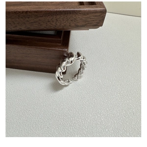 Detail of twisted S925 sterling silver ring featuring chunky croissant texture on wooden base
