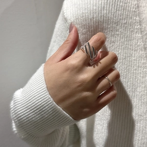 Minimalist S925 sterling silver ring with crisscross pattern on a white knit sweater