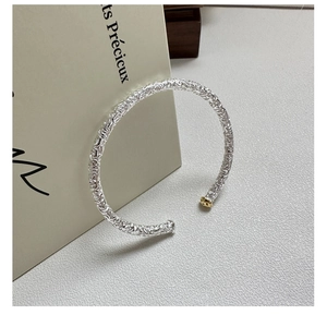 Detailed view of silver S925 cuff with relief patterns and small gold animal accent